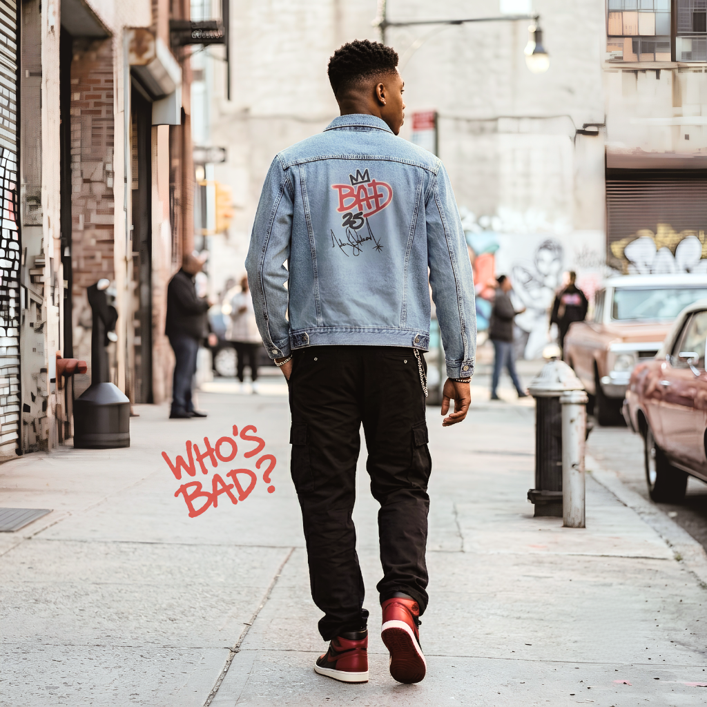 Man walking down a city street wearing a denim jacket with text on the back.