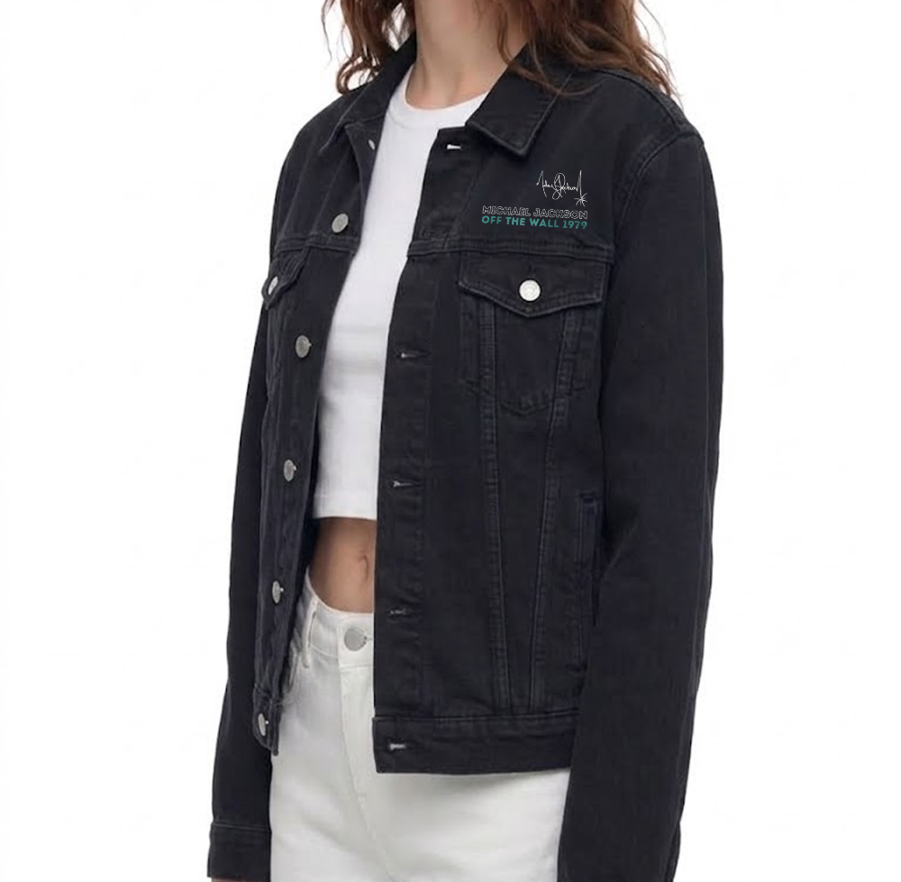A woman wearing a black washed denim jacket with embroidered text on the left chest, layered over a white crop top and white pants, shown against a plain white background.